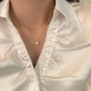 Elegant gold chain necklace with a water drop pearl and metal bear pendant on a model