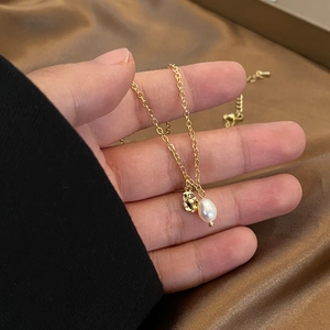 Detail of a natural drop pearl and irregular gold pendant on a minimalist chain