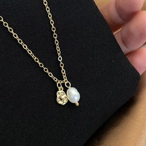 Macro shot of irregular hammered gold pendant and natural white baroque pearl necklace