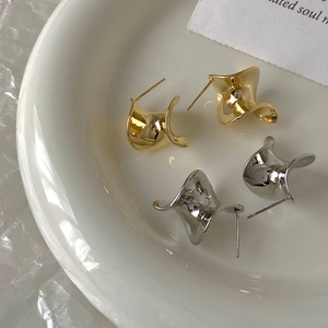 Macro shot of twisted gold and silver hoop earrings on white ceramic tray