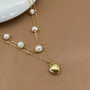 Macro detail of double-layer pearl necklace with a polished gold heart pendant