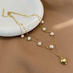 Detail of double-layer necklace with natural freshwater pearls and golden heart pendant