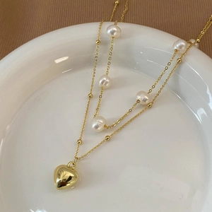 Detail of double-layer gold necklace with freshwater pearls and a heart pendant