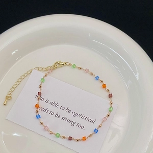 Détail de perles en cristal coloré et chaîne dorée avec fermoir mousqueton réglable sur le bracelet