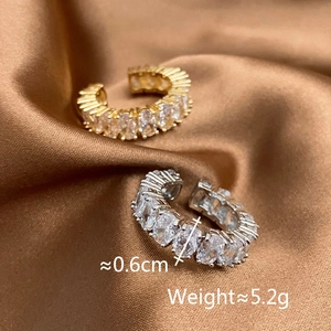 Dettaglio di ear cuff regolabili oro e argento con pavé di zirconi scintillanti
