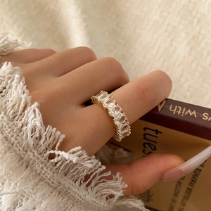 Dettaglio di un anello placcato oro con zirconi ovali indossato sul dito