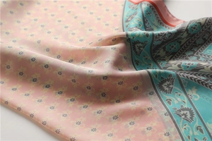 Gros plan d'un foulard en soie montrant des fleurs roses et des motifs bohèmes teal