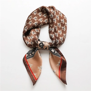 Détail d'un foulard en soie vintage avec motifs floraux dorés et bordure rouge