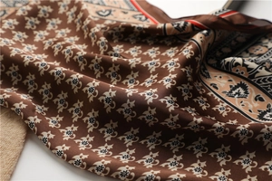 Gros plan détaillé du foulard en soie marron aux motifs floraux et à la texture lisse