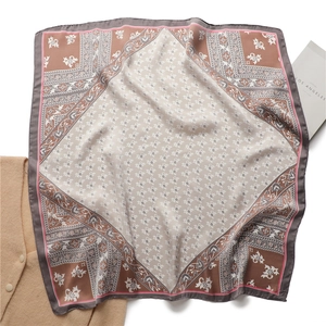 Détail d'un foulard carré en soie avec motifs floraux vintage et bordure baroque élégante
