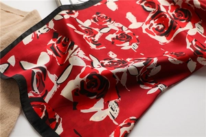 Close-up of a red silk scarf featuring large abstract roses and black border design