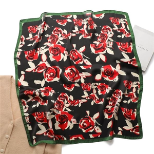 Detail of elegant black silk square scarf with red rose pattern and dark green borders