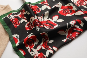 Detailed close-up of red rose print and silk texture on a black retro floral scarf
