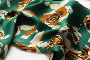 Detailed view of dark green retro silk scarf with elegant floral prints and satin texture