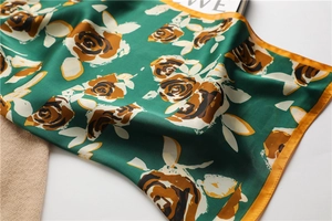 Detailed view of dark green silk square scarf with vintage rose pattern and gold hem