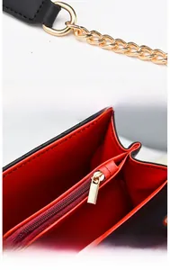 Détail de la doublure en cuir rouge, de la chaîne dorée et de la fermeture éclair en métal