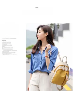 Outdoor street view of a beige and yellow patchwork nylon backpack with FIDM ribbon charm