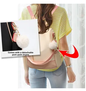 Detail view of pink and beige waterproof backpack featuring a white fluffy pompom charm