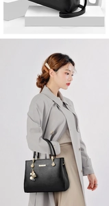 Dettaglio della borsa tote in pelle nera con logo dorato e ciondolo decorativo