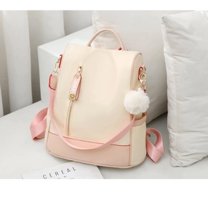 Detail of waterproof nylon backpack with beige pink stitching and pompom charm