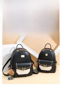 Détail de deux sacs à dos en cuir noir avec rabats blancs et boucles de cerf dorées