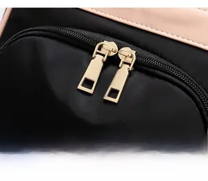 Detail of smooth gold metal zippers on premium black nylon bag with beige leather trim
