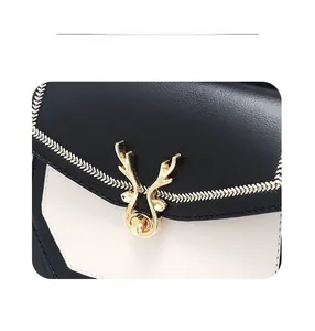 Détail de la boucle dorée en forme de cerf et broderie sur le sac à dos en cuir bicolore