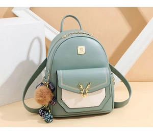 Détail d'un sac à dos en cuir vert avec poche beige et pompon sur support géométrique