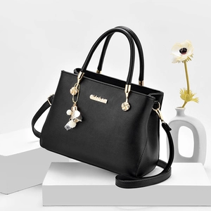 Borsa a mano nera minimalista in ecopelle con finiture dorate e ciondolo di perla
