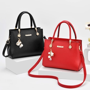 Grande borsa shopper minimalista in pelle nera e rossa con logo oro e ciondolo a fiore