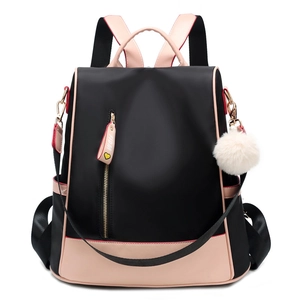 Waterproof nylon backpack in black and pink with vertical zipper and fuzzy ball charm