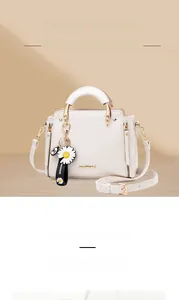 Detail of off-white handbag featuring gold-plated hardware and daisy charm accessory