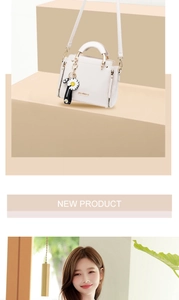 Detail of white leather handbag featuring daisy pendant and metallic zipper accents