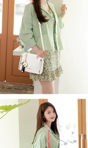 Detail of white leather handbag featuring daisy charm and woven strap on green floral outfit