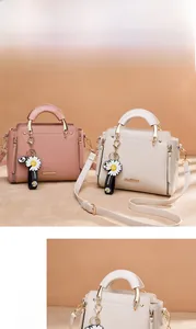 Detail of elegant PU leather handbags in pink and beige with daisy pendants