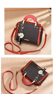 Detail of a brown monogram handbag with red leather trim and daisy charm accessory