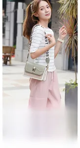 Detail of color-block crossbody bag with gold hardware and wide woven shoulder strap
