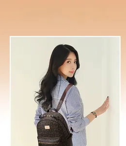Detail of brown leather backpack featuring letter prints and durable metal zipper