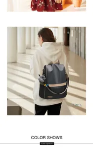 Detail of dark gray anti-theft backpack with plush charm and metal logo on oxford fabric