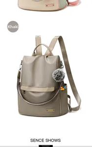 Detail view of khaki nylon backpack with furry pendant and striped shoulder strap
