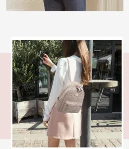Close-up of beige leather mini backpack with pink straps and MOIR letter pattern