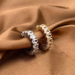 Dettaglio macro di anelli placcati oro e argento con zirconi ovali su tessuto di raso
