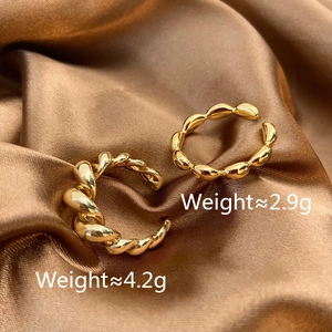Detail of two gold croissant-style and wavy twisted open rings on brown silk fabric