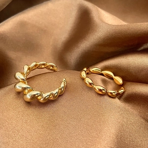 Close-up of gold-plated twisted metal and beaded rings on premium brown satin fabric