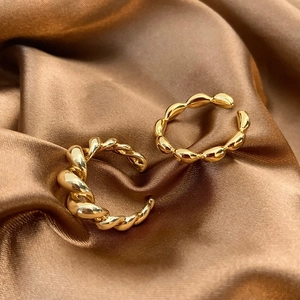 Detailed close-up of 18K gold braided and bamboo-shaped open rings on brown silk fabric