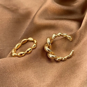 Detailed view of two gold twisted metal rings displayed on a soft bronze satin fabric