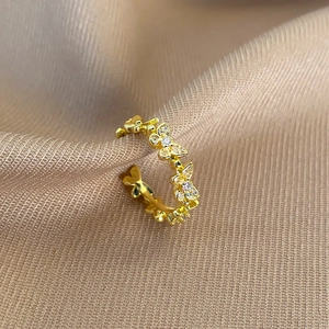 Detailed view of a gold butterfly ring with zircon stones on a silk fabric background