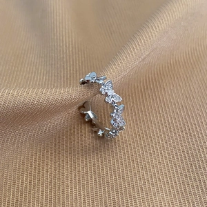 Detailed macro view of silver butterfly ring with shimmering zircon crystals on fabric