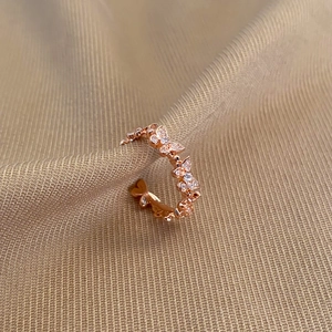 Macro detail of rose gold butterfly ring with zircon wings on soft fabric background