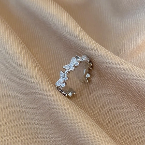 Macro shot of silver butterfly ring with cubic zirconia on champagne silk fabric